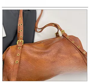 Close-up of brown faux leather shoulder bag with vintage gold eyelets and buckle detail