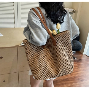 Close-up of woven straw tote bag with brown leather straps and spacious interior