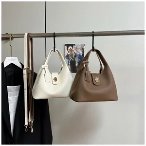 Detail of minimalist leather bucket bags with metal locks and adjustable shoulder straps