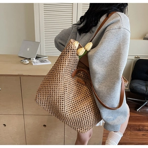 Close-up of woven straw tote bag featuring brown leather straps and hollow weave texture