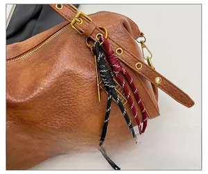 Detail of brown litchi pattern leather bag with vintage gold zipper and woven charm