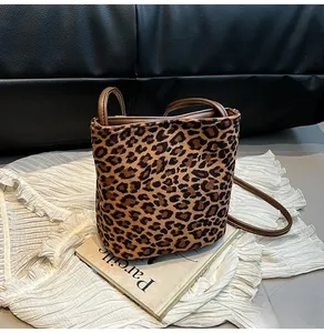 Détail du sac seau à motif léopard avec poignée en cuir marron et texture peluche