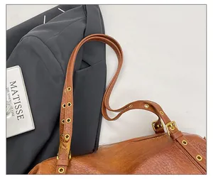 Detail of retro brown lychee leather shoulder bag with adjustable eyelet strap