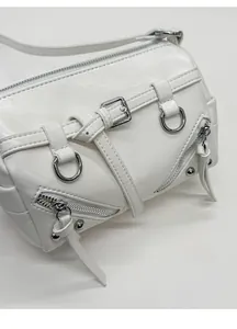 Detailed macro view of white pebble leather texture and silver rivets on the motorcycle bag