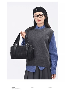 Close-up of black woven texture cylinder bag with wide handle and silver metal hardware