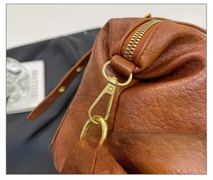 Detail shot of caramel brown lychee leather texture and golden metal hardware on shoulder bag