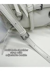 Detail of white leather shoulder strap with silver buckle and multi-hole adjustment