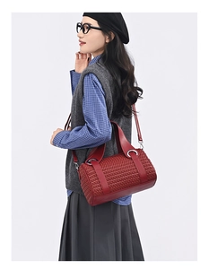 Close-up of woven red leather barrel bag showing metal ring hardware and shoulder strap
