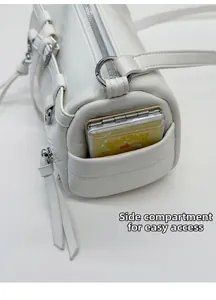 Detailed side pocket of white cylinder crossbody bag showing storage capacity and tassels