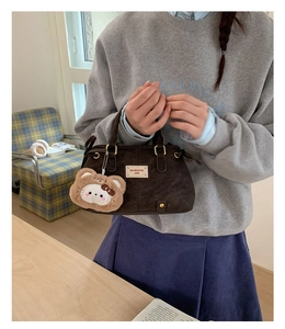 Detail of dark brown suede handbag with vintage handle and plush animal charm