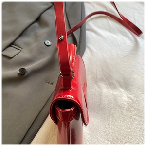 Detail of red wax leather mini flap bag featuring polished finish and adjustable strap