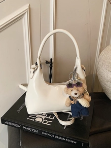Retro cream hobo bag with teddy bear charm on art books, minimalist chic style