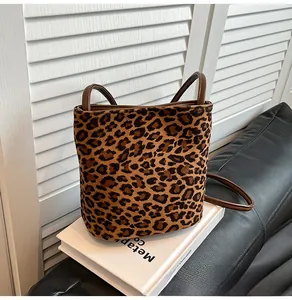 Détail du sac seau à imprimé léopard avec poignées et bandoulière marron sur livre blanc