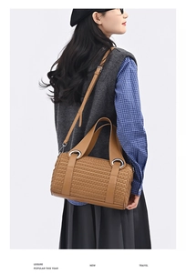 Detail showing the brown woven texture and silver metal rings of the stylish cylinder bag