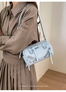 Close-up of light blue pillow bag with belt buckles and zippers on a khaki coat