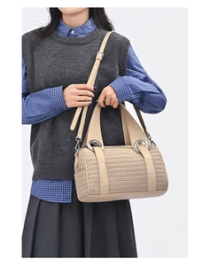 Detail of beige woven Boston bag with adjustable strap and silver metal rings