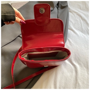 Detail of red oil wax leather handbag showing magnetic closure and herringbone lining