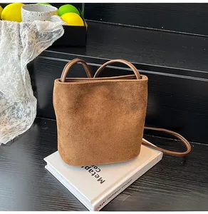 Vue détaillée d'un sac seau en daim marron mat avec poignées rondes sur des livres déco