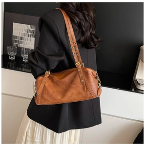 Close-up of caramel Boston bag with metal eyelet strap detail worn over the shoulder