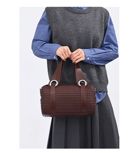 Detail of dark brown woven pillow bag showing silver ring handles and texture