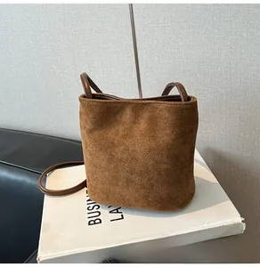 Détail d'un sac seau en daim marron avec des anses en cuir foncé et un style vintage