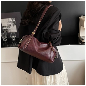 Detail of vintage burgundy textured leather shoulder bag with gold metal eyelet accents