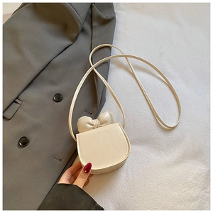 Détail d'un mini sac à bandoulière blanc crème avec nœud 3D et texture en similicuir PU