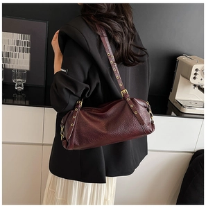 Detail of dark red lychee leather bag with decorative long straps and gold eyelets
