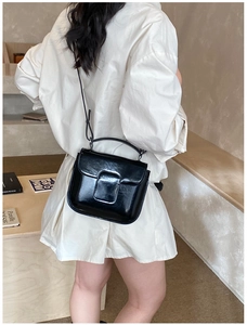 Close-up of black oil wax leather handbag shown with crossbody strap in cozy room