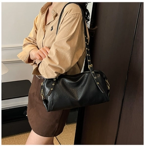 Detail of black pebbled leather Boston bag with gold eyelet strap and metallic zipper