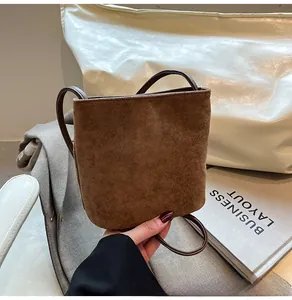 Gros plan d'un mini sac seau en daim marron mat avec bandoulière en cuir élégante
