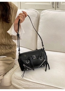 Detail of vintage black tote bag with silver rivets and zippers in a minimalist setting
