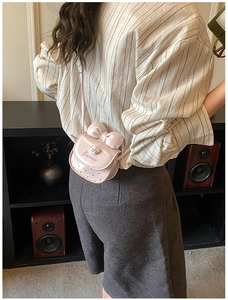Détail du mini sac à bandoulière rose avec nœud décoratif, breloque et broderie fine
