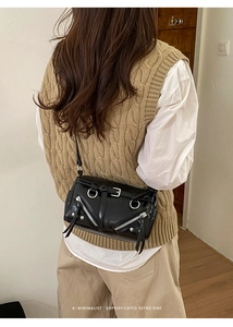 Close-up of retro black biker bag with silver metal zippers and stud details