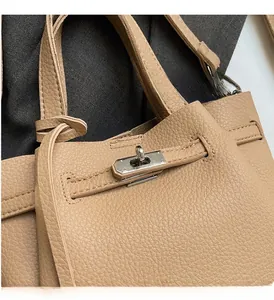 Gros plan du fermoir rotatif argenté et des brides en cuir d'un sac à main marron