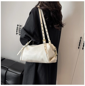 Detail of cream leather shoulder bag featuring dual eyelet straps and gold hardware
