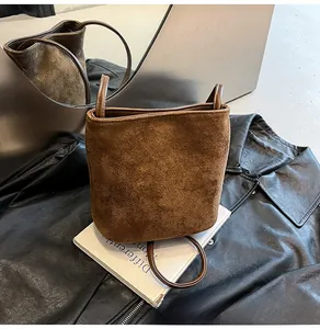 Détail du sac seau minimaliste en daim marron foncé mat avec garniture en cuir lisse