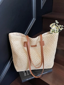Handwoven straw tote bag with brown leather handles and interior fabric lining
