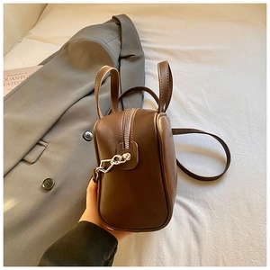 Detail of dark brown leather handbag showing silver hardware and side zipper profile
