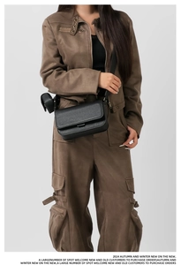 Detailed view of a black pebble leather crossbody bag with wide strap and round coin purse