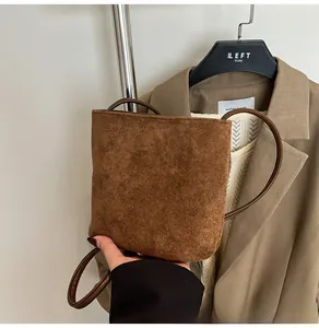 Détail d'un petit sac à main en daim marron vintage sur fond de blazer kaki