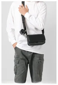 Detail of matte black leather crossbody bag with adjustable strap and small earphone pouch