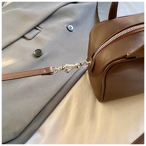 Detail of silver buckles and stitching on dark brown leather shoulder bag