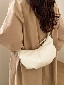 Minimalist creamy white leather crescent bag with soft pleated design worn by a model