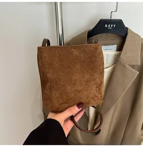 Gros plan d'un sac à bandoulière en daim marron avec une texture mate et une sangle
