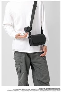 Detail of black matte leather crossbody bag with metal rivets and detachable mini cylinder pouch