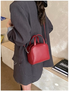 Detail of dark red crossbody leather bag styled with a professional grey blazer jacket