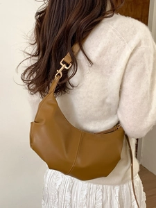 Minimalist brown crescent hobo bag with soft pleated design and golden metal accents