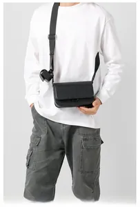 Detail of black crossbody bag with wide shoulder strap and functional small pouches