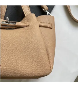 Détail de sac seau en cuir grainé beige avec boucle en métal argenté et texture de luxe